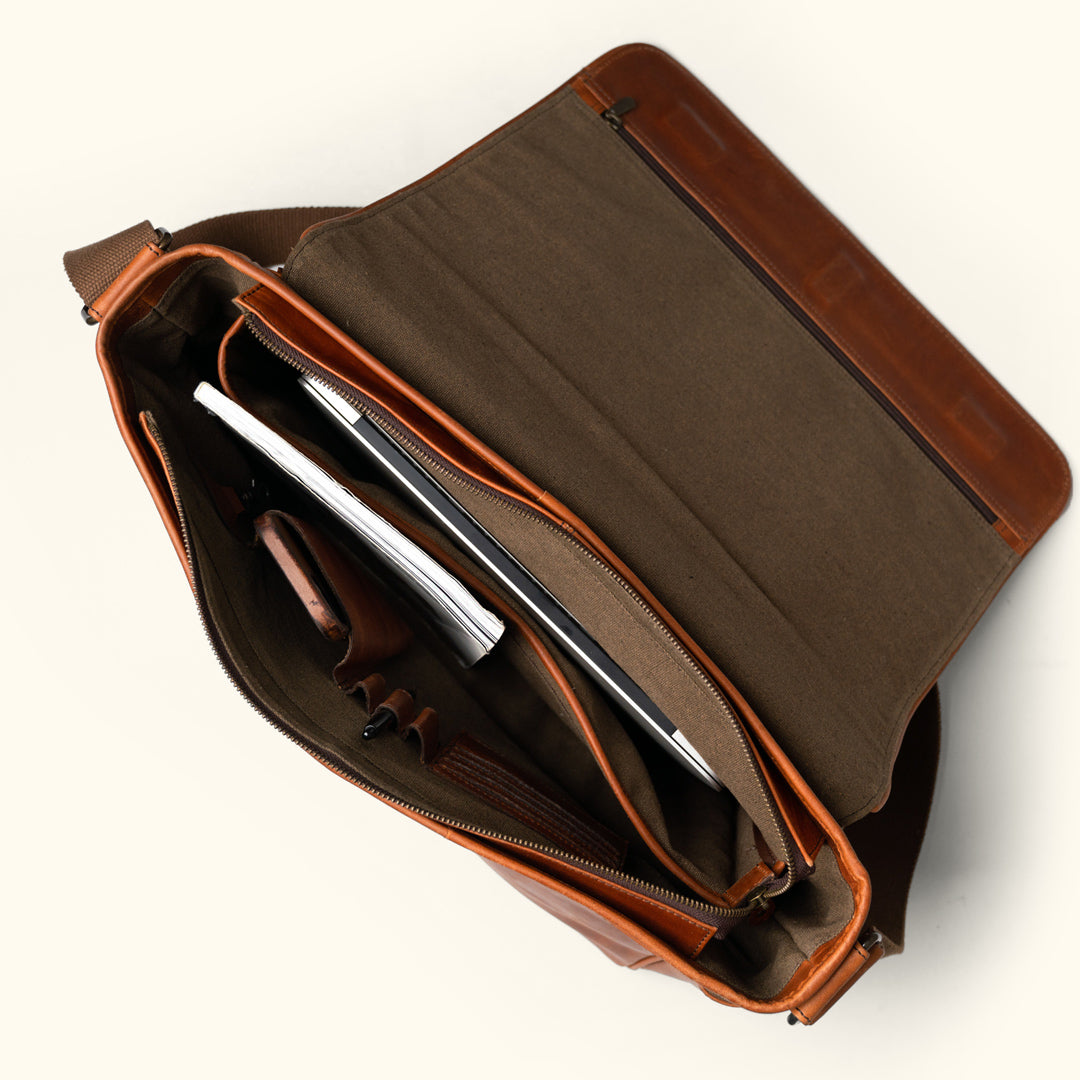 Spacious Roosevelt leather satchel in rich amber brown with secure flap and reinforced stitching.
